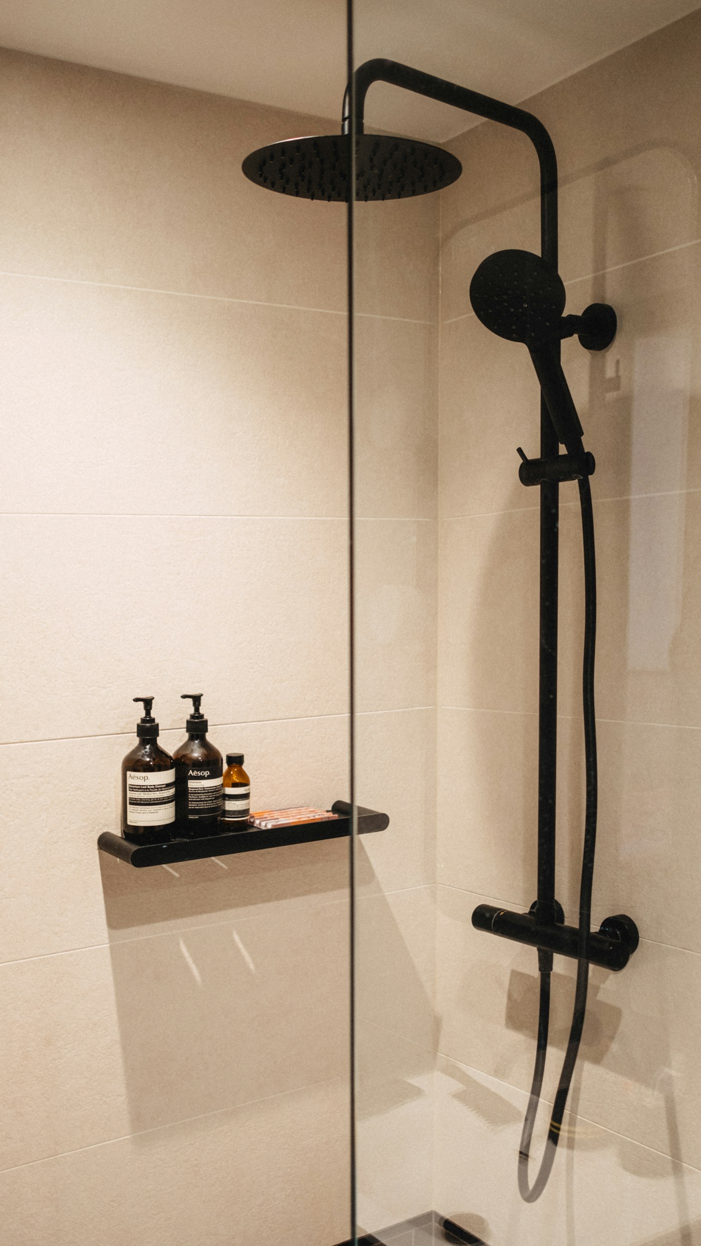 Close detail of large-format shower tile with a matte black fixture