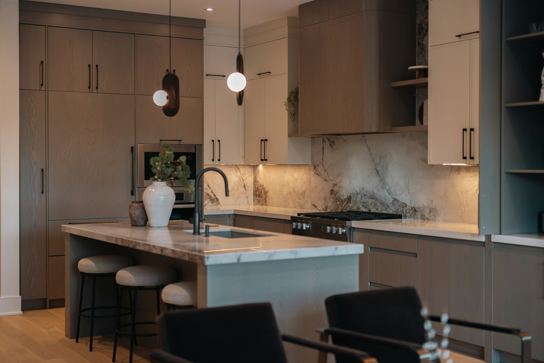 Kitchen with warm wood cabinetry, a stone island and pendant lighting