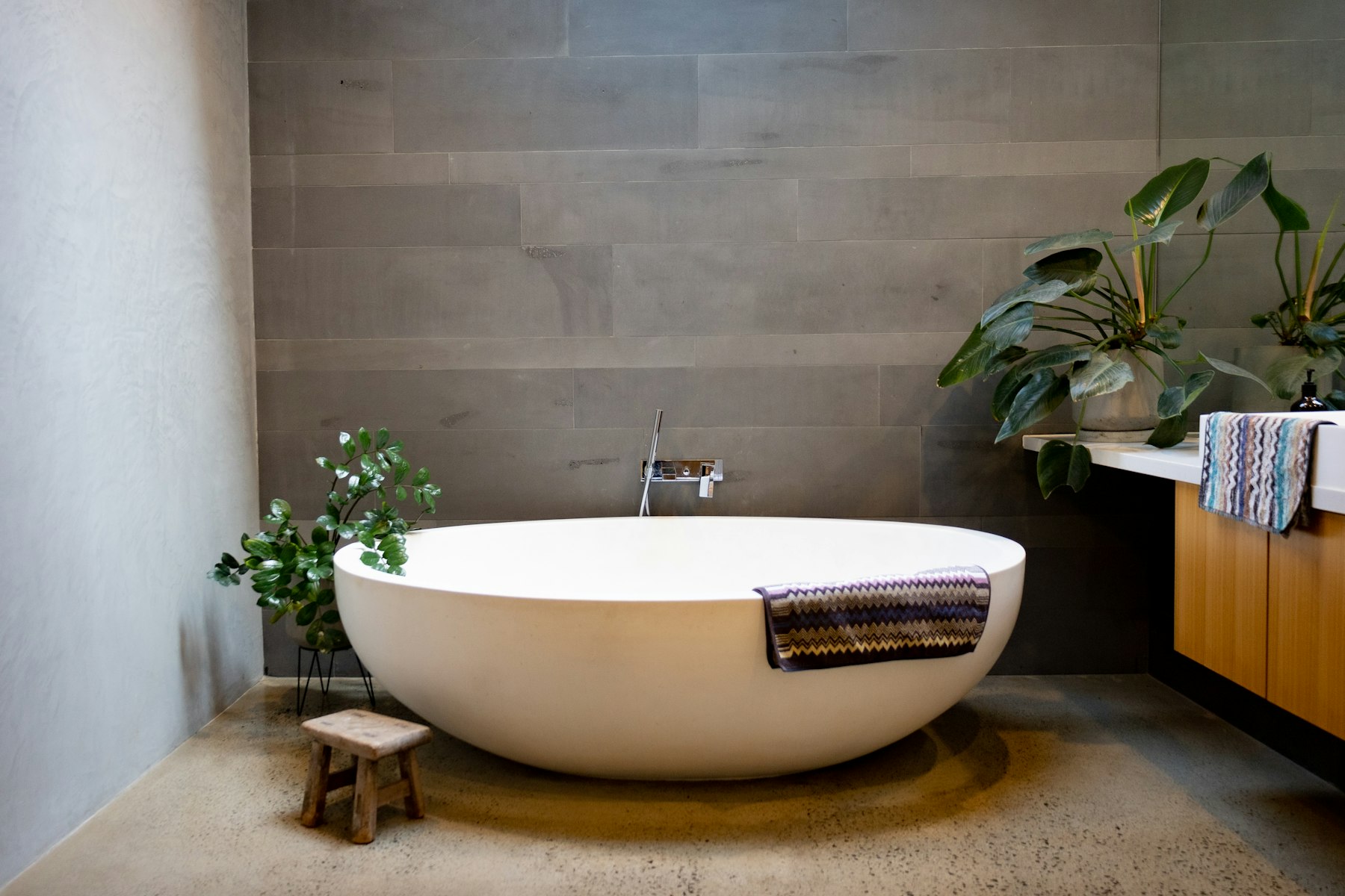 Spa-style bathroom with a freestanding tub, wood vanity and greenery