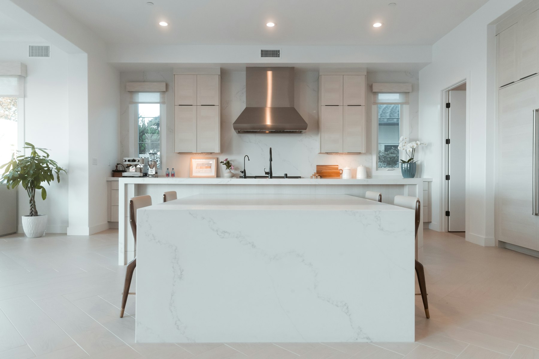 Kitchen remodel with marble countertops, white cabinetry and a plaster range hood